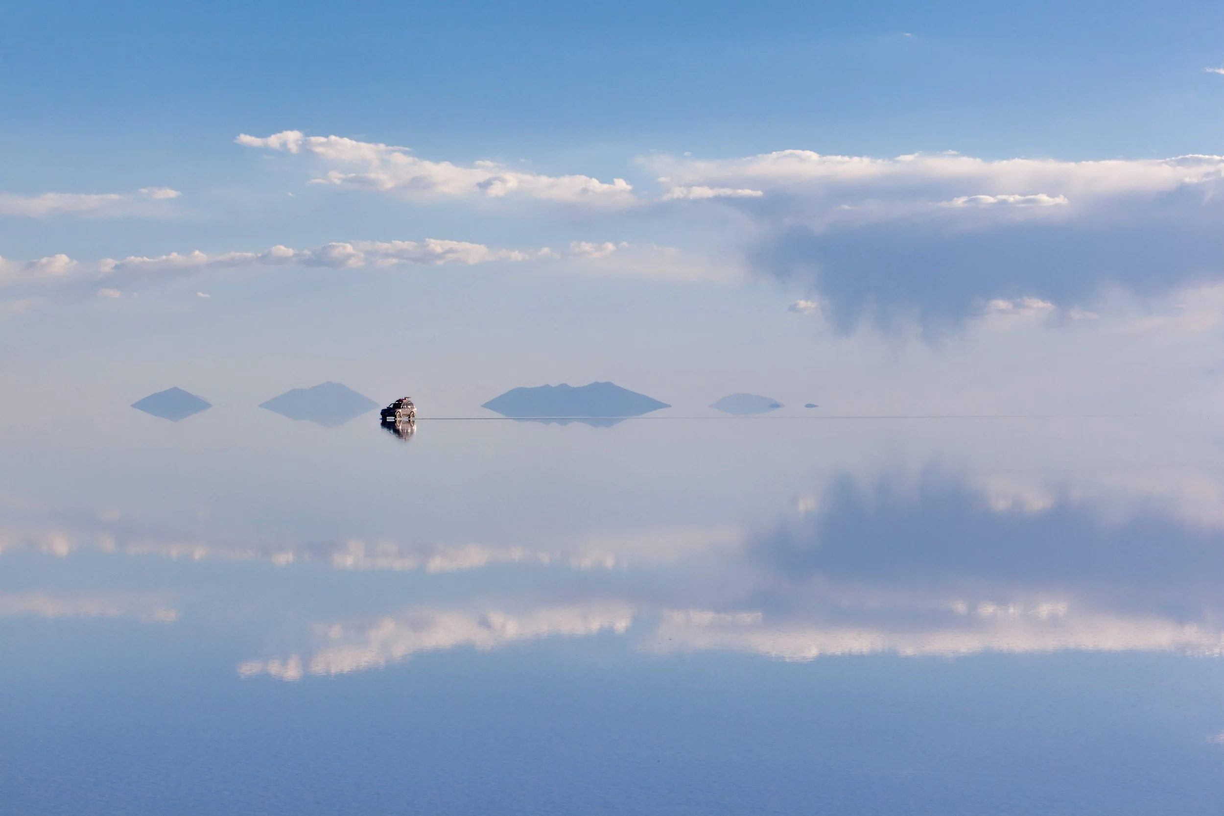 A lone vehicle crossing the mirror of the Salar de Uyuni, Bolivia